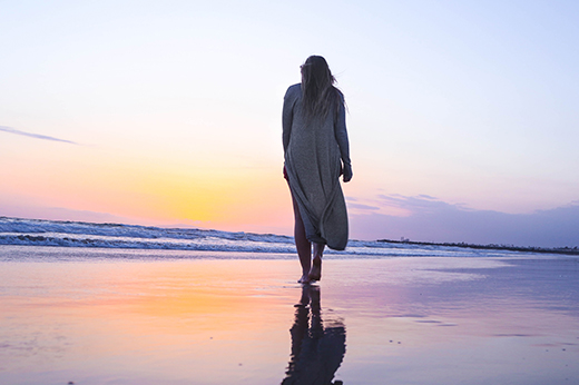 woman walking along beach to symbolize fertility journey